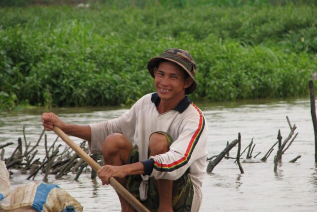A fishman steers his tiny craft through the weeds.