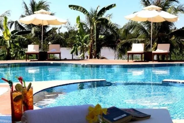 Pool, parasols and coconut palms at the Ben Tre eco lodge